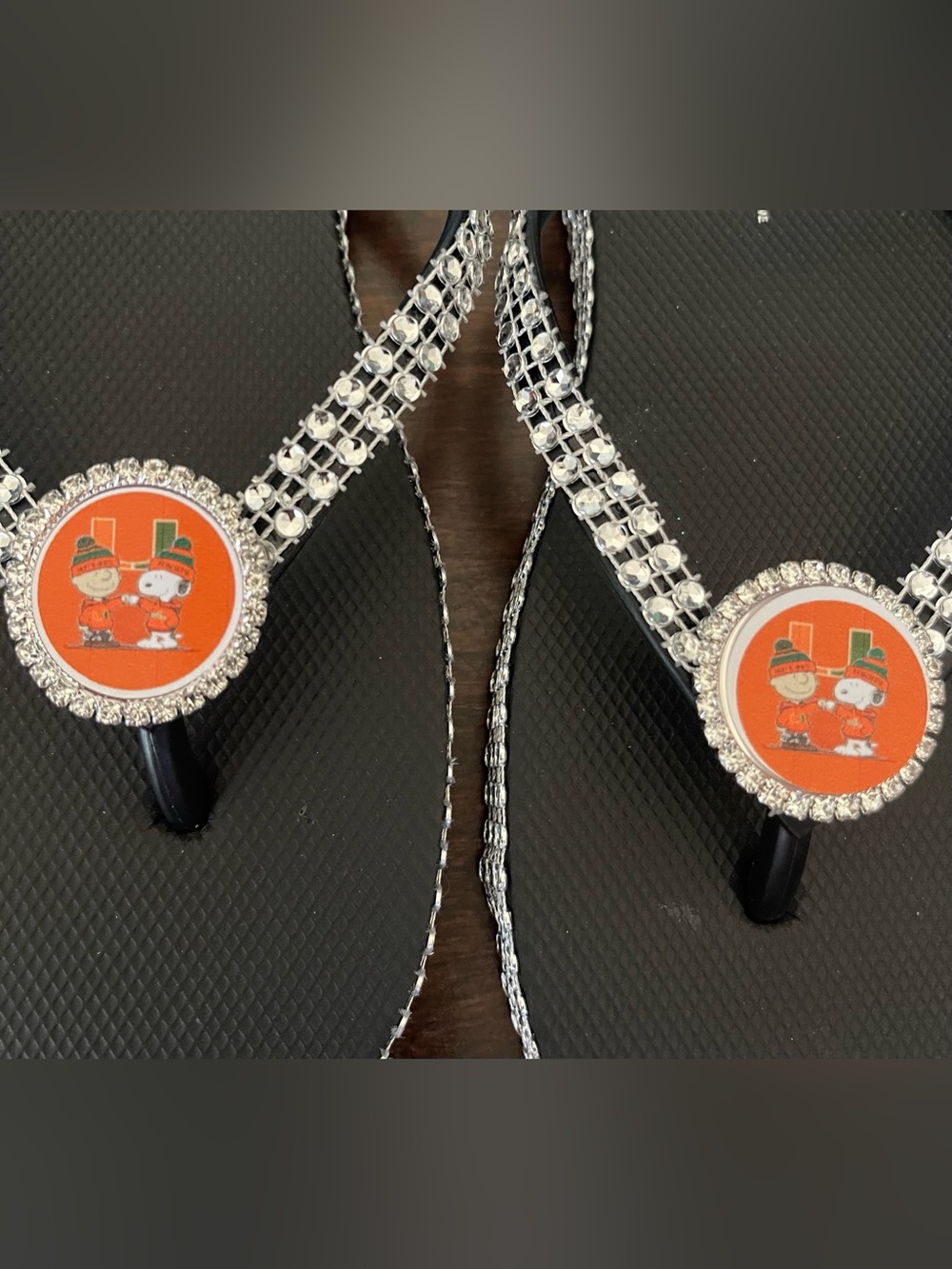 Peanuts x Womens Rhinestone Black Flip Flops with Orange Character Medallions